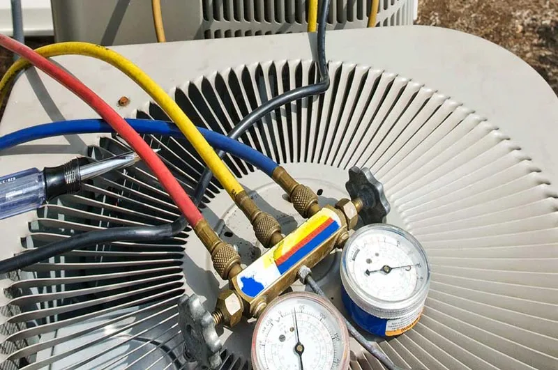 Technician’s refrigerant gauges on an outdoor air conditioner